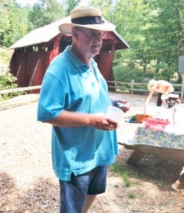 Joe Hamrick talks to the Landrum Garden Club in front of Campbell’s  Covered Bridge. At right is Charlotte Hamrick preparing for the club’s picnic. (photo submitted)