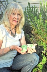 Soap-maker Linda Bond raises many of the plants used for her soaps. She’s holding bars of soap made with parts of the rosemary bush shown in this photograph.