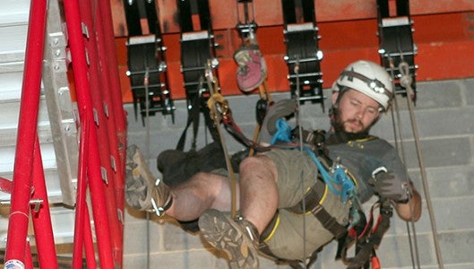 Nick Rutz, one of the three men with Imagine Design and Production Services, Inc. commissioned to work on the rigging renovation project, works on putting in new pulleys for the upgraded rigging system above the Veh Family Stage. (Photo submitted by Chris Bartol)