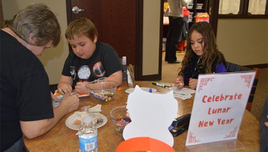 Zavier Greene and Ciera Weathers colored traditional dragon cutouts at the Chinese New Year celebration.